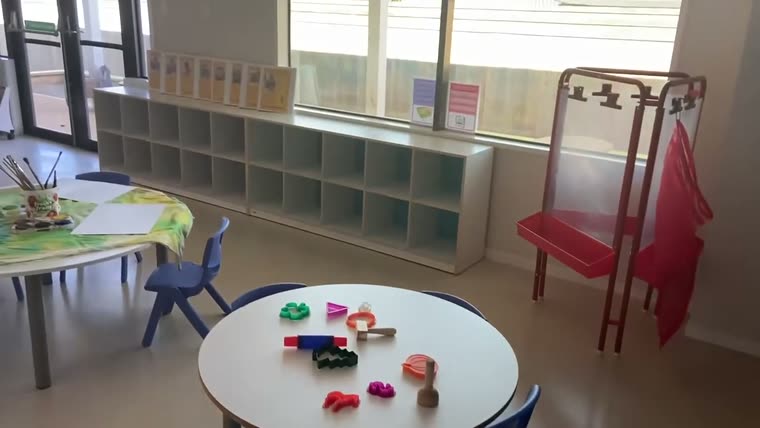 A round table with small blue chairs and open shelving behind