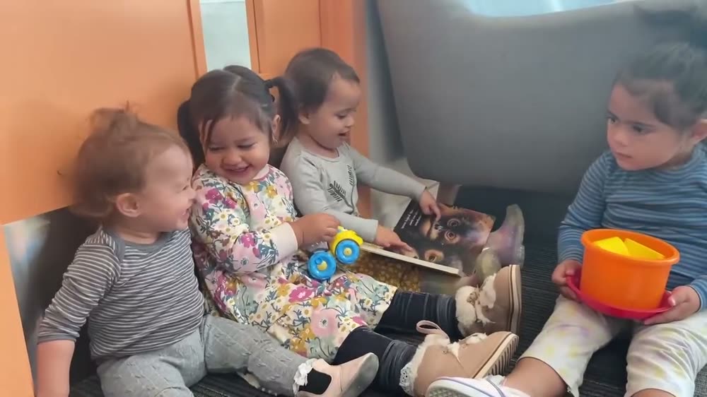 A group of children sitting together on a couch looking at a picture book